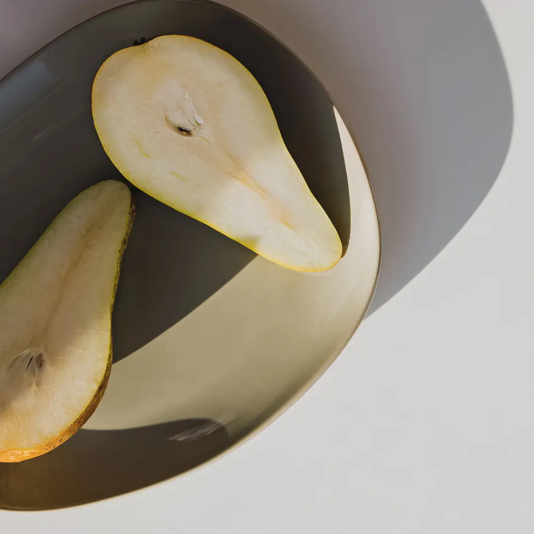 dekoration: Eine aufgeschnittene Birne liegt in einer minimalistischen Schale.