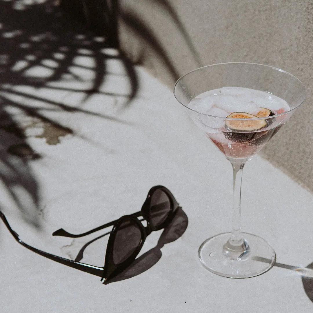 dekoration: Eine Sonnenbrille und ein Cocktailglas auf einem Tisch im Sonnenlicht.