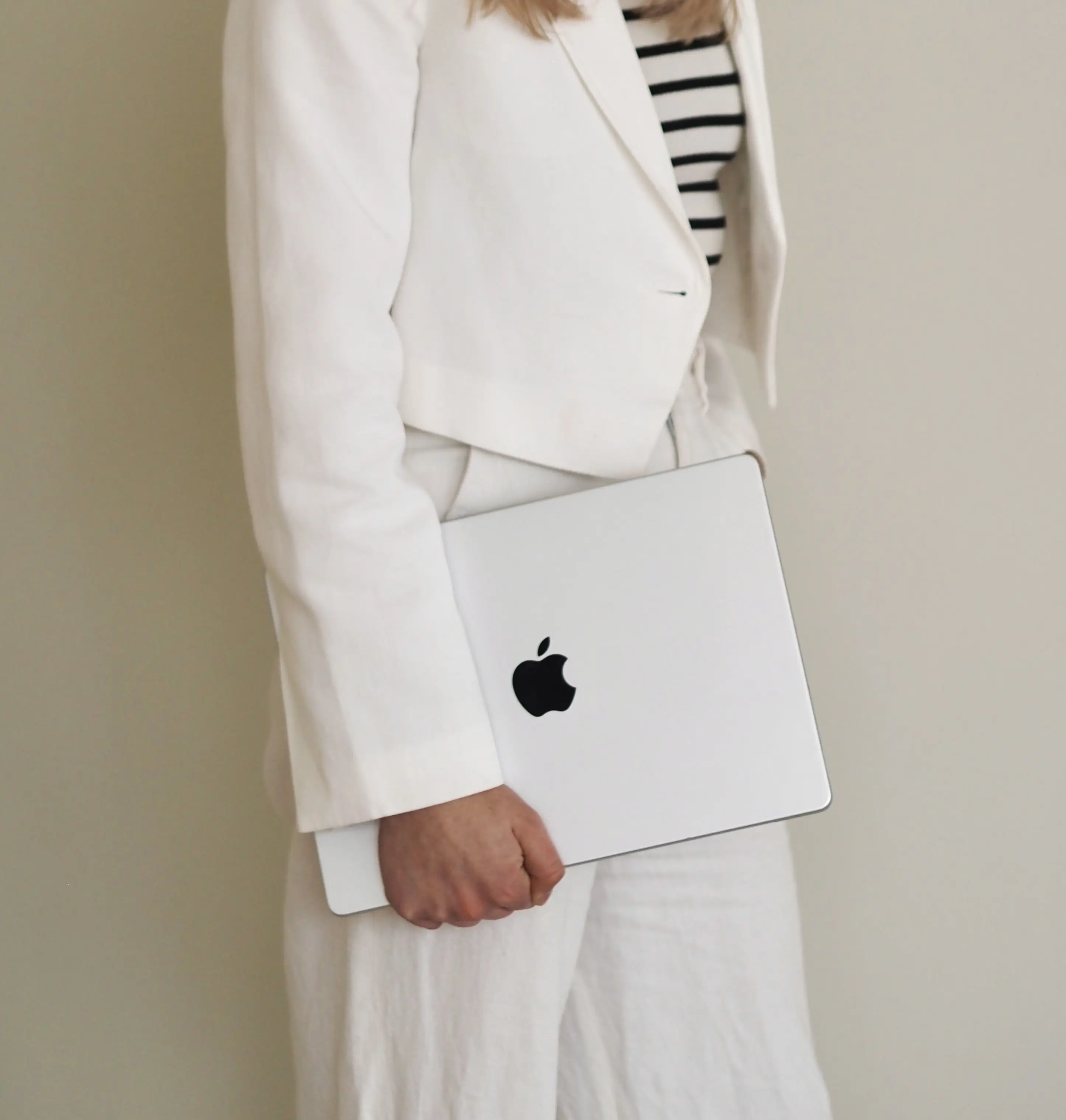 Eine Person in einem weißen Outfit trägt einen Laptop unter dem Arm, symbolisch für Social Media Management.